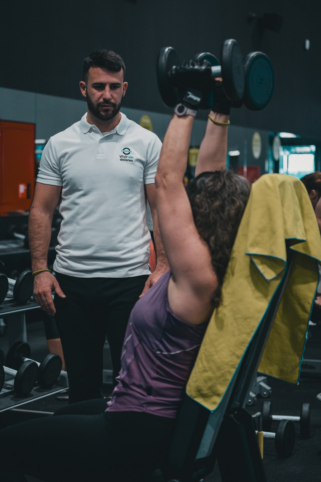 Sesión de entrenamiento en el gimnasio con un entrenador personal, enfocada en el rendimiento y el bienestar físico.