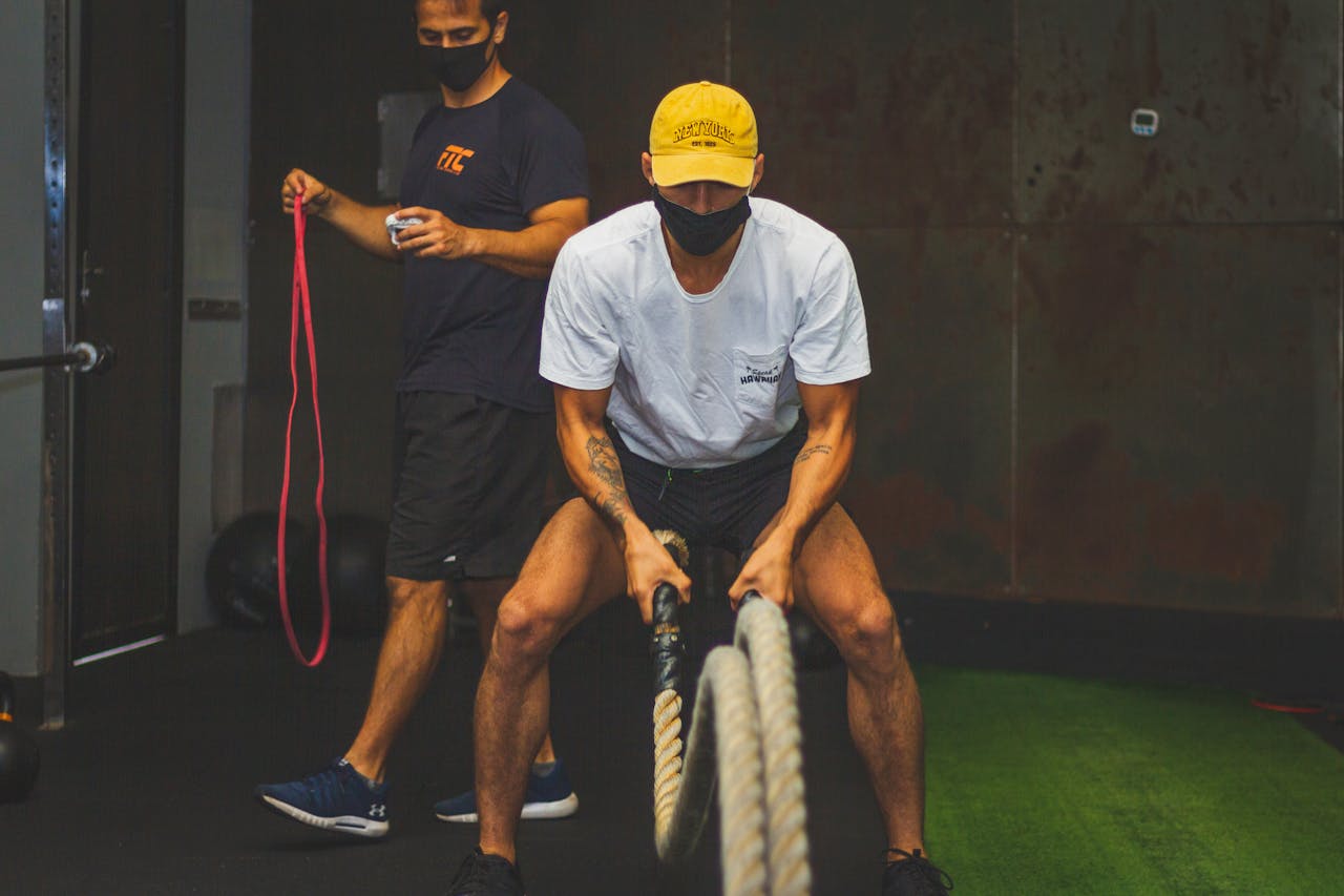 Two men engaged in a dynamic workout using battle ropes and resistance bands indoors.